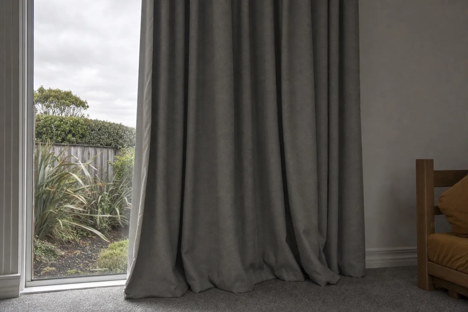 Illustrative photo: a heavy lined curtain drawn across a window in a plain room.