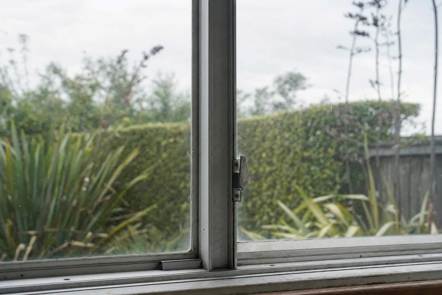 Illustrative photo: the centre mullion of an older aluminium window, with the latch on the opening sash.