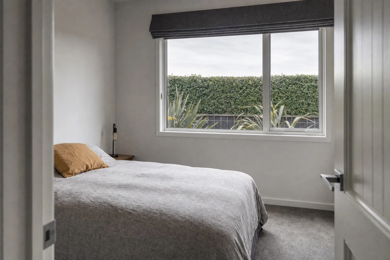 Illustrative photo: a single bedroom window seen from the doorway of a plain room.