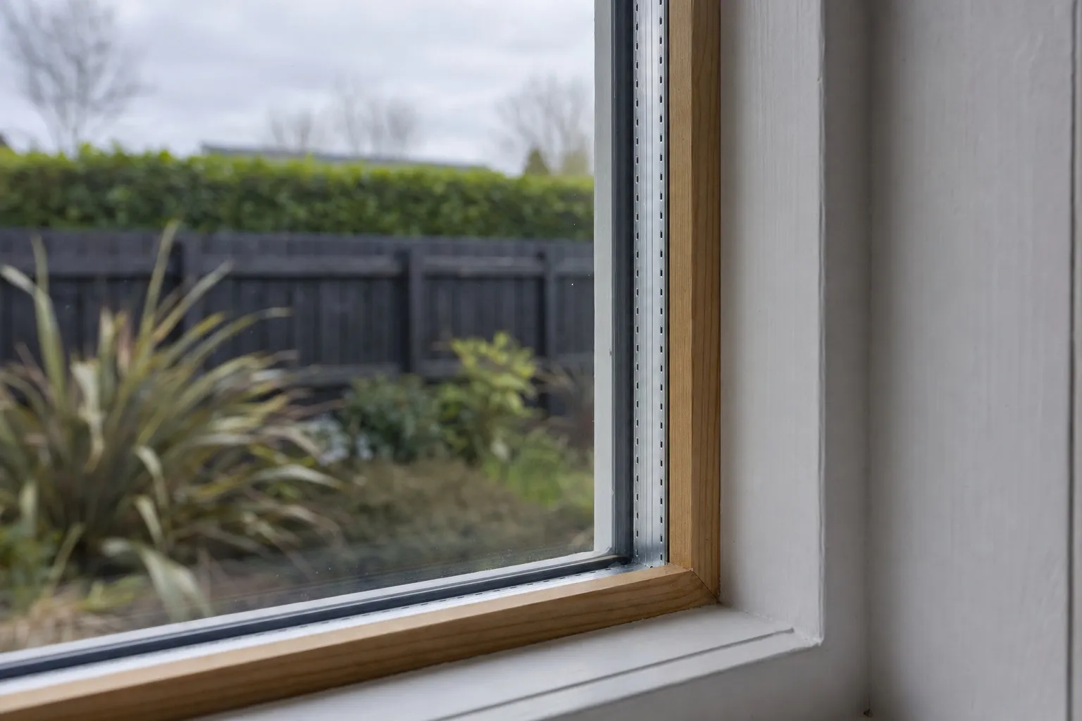 Illustrative photo: the edge of a double glazed unit in a timber sash, with the spacer bar visible between the two panes.